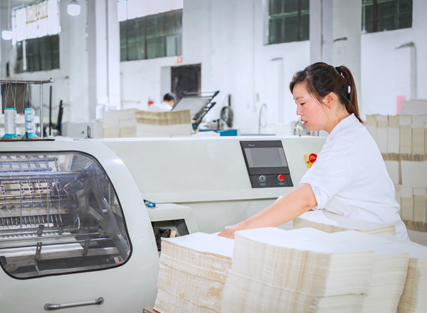 a female worker in white uniform is checking printing procedure of notebooks