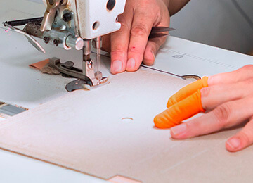 a worker sewing a cover of a notebook