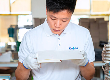 a male worker in white uniform with Kinbake logo is checking a finished notebook