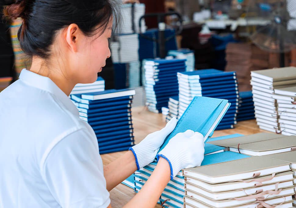 a female work wearing a glove is examining on a batch of notebooks