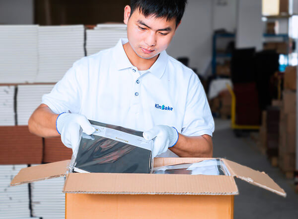 a male worker is putting a notebook into a carton with many other notebooks