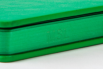 a green notebook with custom laser cut letters edge spraying