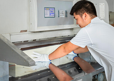 a male worker is setting a machine knife for cutting notebooks