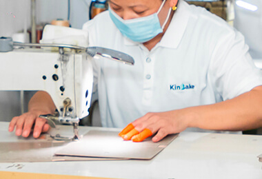 a worker wearing a dust mask is sewing a cover of a notebook