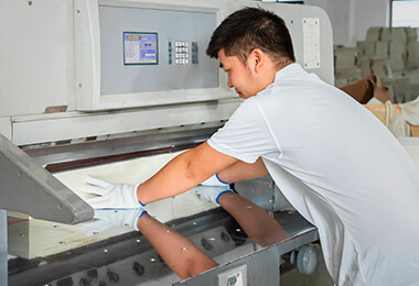 a male worker is setting a machine knife for cutting notebooks