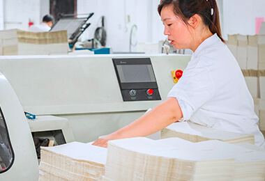 a female worker in white uniform is checking paper binding procedure of notebooks